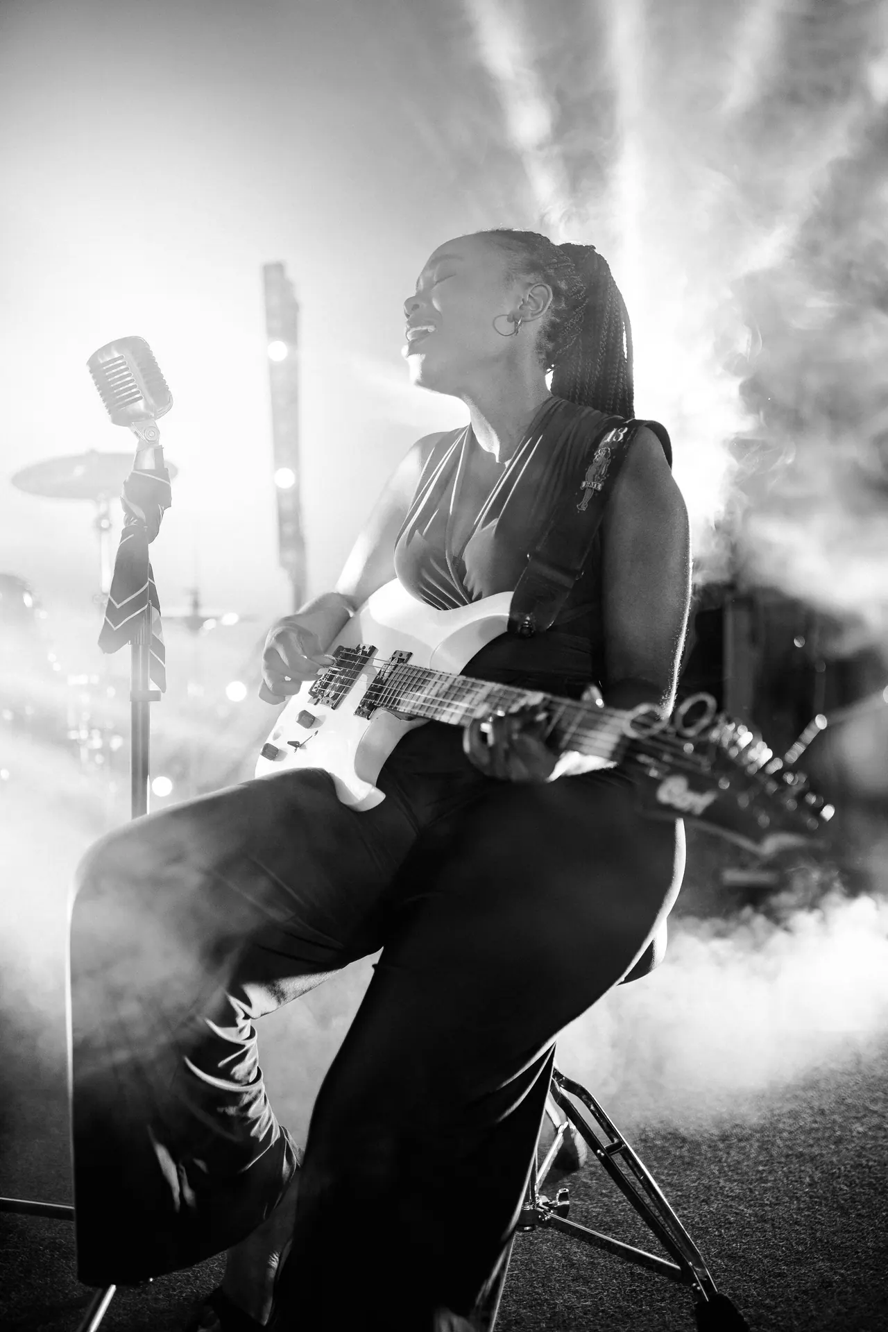Imani Vey en blanco y negro, sentada con la guitarra blanca